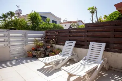 two white chairs sitting on a patio next to a fence at Spyros No23 Charming Oceanview Maisonette in Meneou