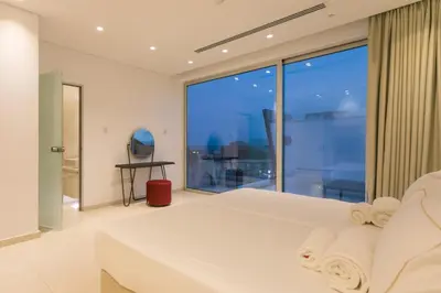 a bedroom with a white bed and a large window at Cove Seaview Villas - Nautica in Ayia Napa