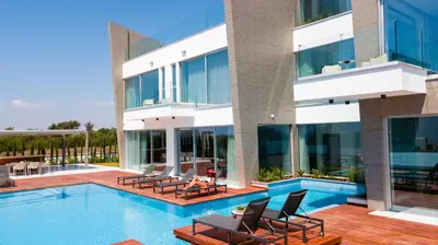 a large building with a swimming pool and chairs at Cove Seaview Villas - Nautica in Ayia Napa