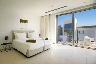 a white bedroom with a bed and a large window at Cove Seaview Villas - Neptune in Ayia Napa