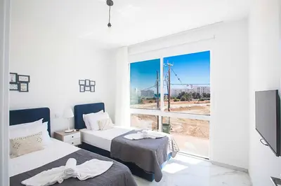 a bedroom with two beds and a large window at Vie Bleu 1 in Protaras