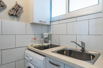 a white kitchen with a sink and a window at Berries 1-BR Apt in Larnaca in Larnaka