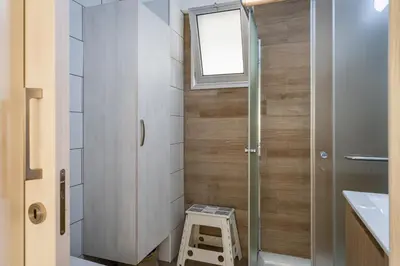 a small bathroom with a stool next to a window at Berries 1-BR Apt in Larnaca in Larnaka
