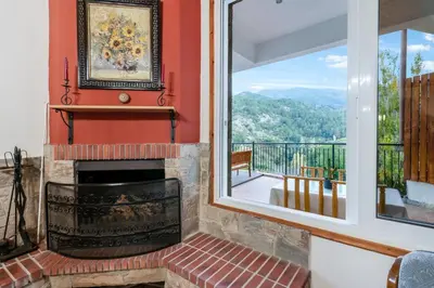 a living room with a fireplace and a balcony at House Eufrosyne in Moutoullas