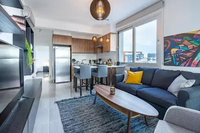 a living room with a blue couch and a kitchen at Sunflower 1-Bedroom Apartment in Larnaca in Larnaka