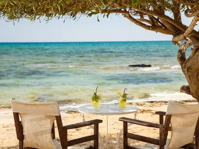 a table on the beach with two chairs and drinks at Sanders Only in Limassol