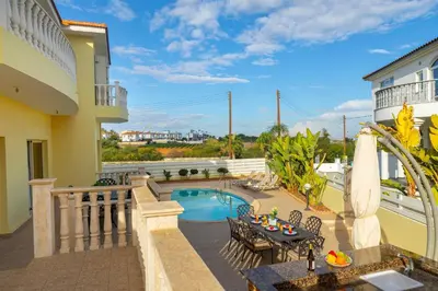 a balcony with a pool and a table and chairs at Protaras Posidon By The Sea in Protaras