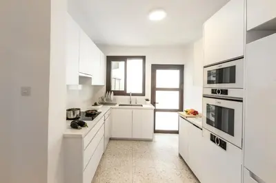 a white kitchen with white cabinets and appliances at Platres Forty Pine Trees Cottage in Platres