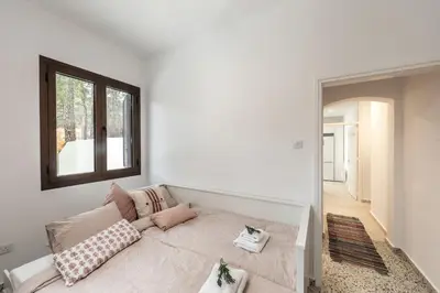 a white room with a bed with pillows and a window at Platres Forty Pine Trees Cottage in Platres