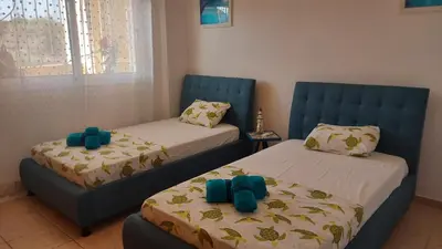 two beds in a room with blue chairs at NISSI GOLDEN SANDS SEA VIEW 2 BEDROOM Apartment in Ayia Napa