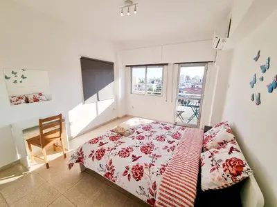 a bedroom with a bed and a desk and window at City View Rooms in Larnaka
