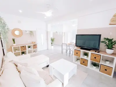 a white living room with a white couch and a tv at Shelter next to the beach in Larnaka