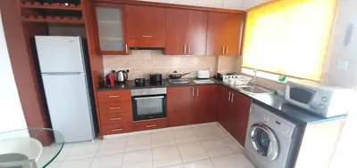 a kitchen with wooden cabinets and a white refrigerator at Vasilas Holiday Apartment #2 in Larnaka