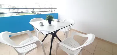 a white table and four white chairs in a room at Vasilas Holiday Apartment #2 in Larnaka