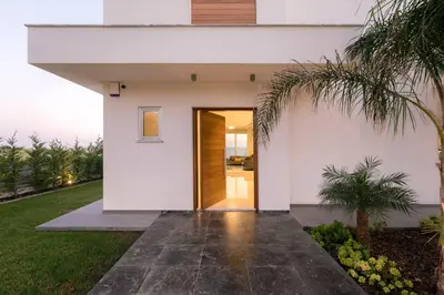 a pivot door in a white house with palm trees at Sea Pearl Beachfront Villas - Breeze in Ayia Napa