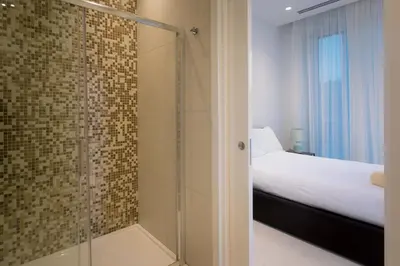 a glass shower in a bedroom with a bed at Sea Pearl Beachfront Villas - Anemone in Ayia Napa