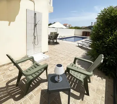 two green chairs and a table on a patio at Nissi Beach Golden Villas in Ayia Napa