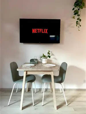 a table with chairs and a tv on a wall at Central Ground Floor Apartment in Nicosia