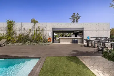 a building with a pool and a patio with tables and chairs at Sunset Gardens in Limassol