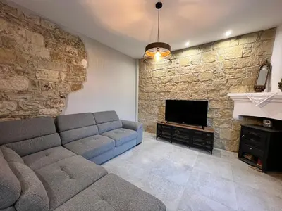 a living room with a couch and a stone wall at Eftis - Renovated Traditional House in Omodos