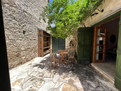 a patio with a table and chairs next to a building at King's house in Lofou