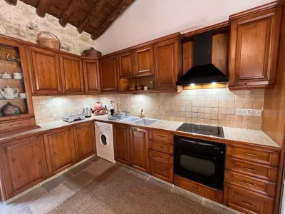 a kitchen with wooden cabinets and a stove top oven at King's house in Lofou