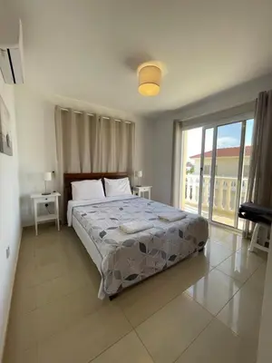 a bedroom with a large bed and a balcony at Nissi Villa in Ayia Napa