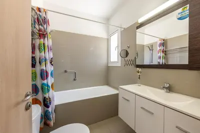 a bathroom with a tub and a sink and a toilet at Flouressia Gardens Villas in Protaras