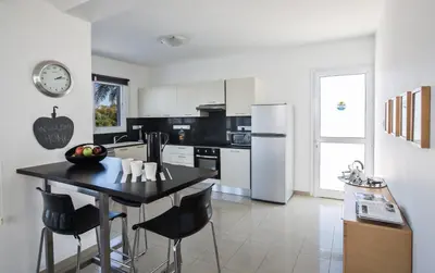 a kitchen with a black table and a white refrigerator at Flouressia Gardens Villas in Protaras
