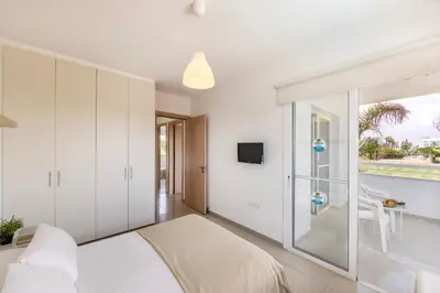a bedroom with a bed and a sliding glass door at Flouressia Gardens Villas in Protaras