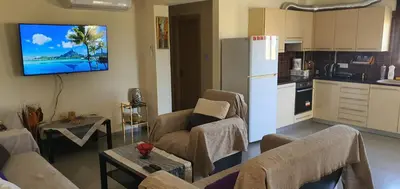 a living room with couches and a kitchen with a refrigerator at STEFARIS PROPERTIES 'sioukris court' in Larnaka