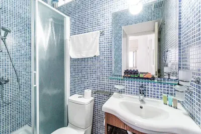 a blue tiled bathroom with a toilet and a sink at Villa Elliana by Ezoria Villas in Protaras