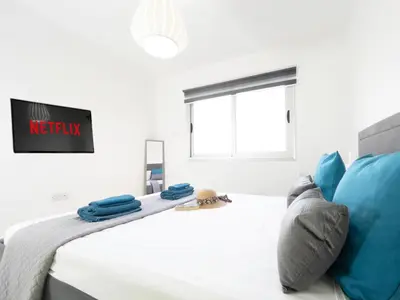 a white bedroom with a bed with blue pillows at Pandora Holiday Apartment Ayia Napa in Ayia Napa