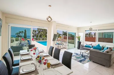 a dining room with a table and a living room at Villa Mesogeios ME16 in Protaras