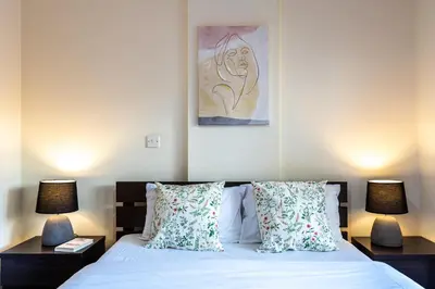 a bedroom with a bed with two lamps and a painting at Freya 1-Bedroom Apartment in Larnaca in Larnaka