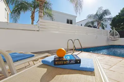 a swimming pool with a swing and an orange on a towel at Villa Clara in Protaras