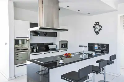 a kitchen with a black counter and stools at Villa Pallas KO1 in Protaras