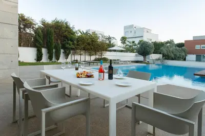 a white table and chairs with wine bottles and food at Vivo Mare Beachfront Villas - Emerald in Ayia Napa