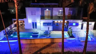 a house with a swimming pool at night at Tsolias Apartments in Protaras
