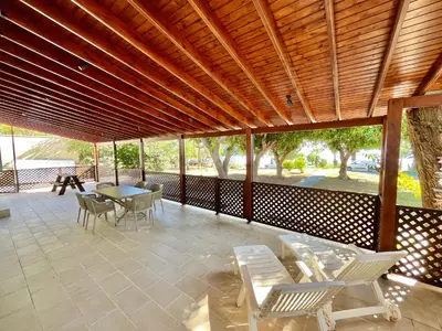 a covered patio with chairs and a table and a table and chairs at Dream Beachfront Bungalow in Limassol