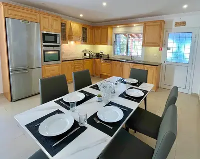 a kitchen with a table and chairs and a kitchen with a refrigerator at Dream Beachfront Bungalow in Limassol