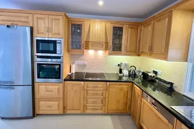 a kitchen with wooden cabinets and a stainless steel refrigerator at Dream Beachfront Bungalow in Limassol