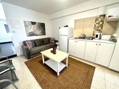 a living room with a couch and a table in a kitchen at Harbour Seaside Escape in Ayia Napa