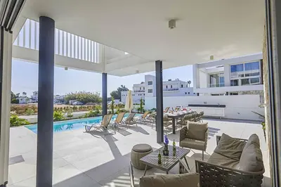 a patio with chairs and a table and a pool at Nissi Kube KB1 in Ayia Napa