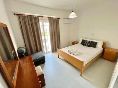 a bedroom with a bed and a couch and a window at Two Bedroom City Seaside Apartment in Limassol