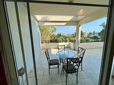 a patio with a glass table and chairs on a balcony at Two Bedroom City Seaside Apartment in Limassol