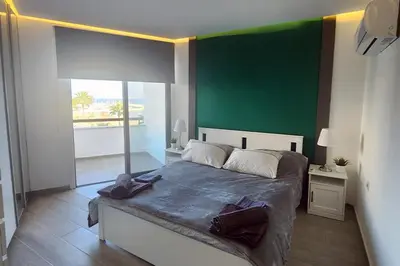 a bedroom with a large bed with a green wall at Prime Beachfront Apartment on Larnaca Finikoudes in Larnaka