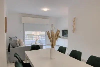 a white table with green chairs and a vase with flowers at Phaedrus Living Down Town Flat Stephania 302 in Limassol