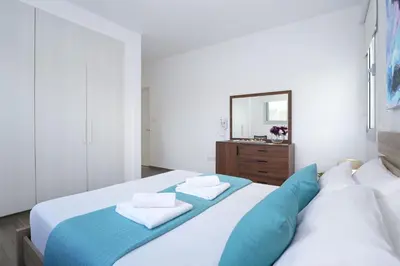 a bedroom with a bed with blue pillows and a mirror at Villa Catalina in Ayia Napa