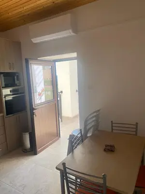 a dining room with a table and a kitchen with a door at TheonikosHouse in Agros